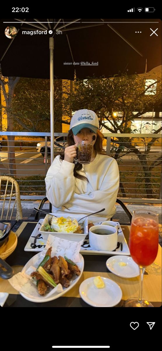 a person sitting at a table with food and drinks