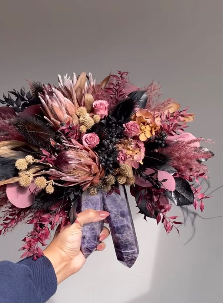 a person holding a bouquet with flowers and feathers