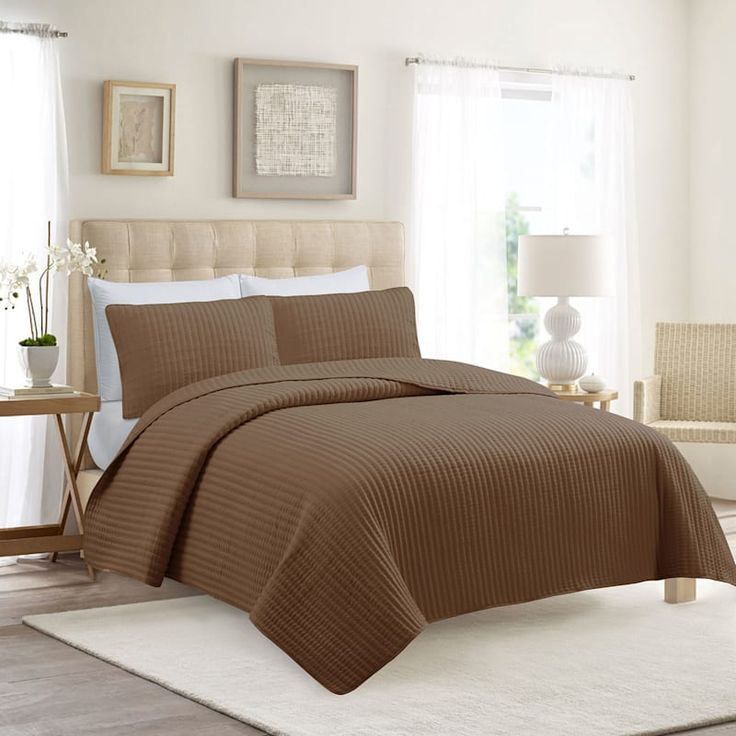 a bed with a brown bedspread in a bedroom next to a white rug