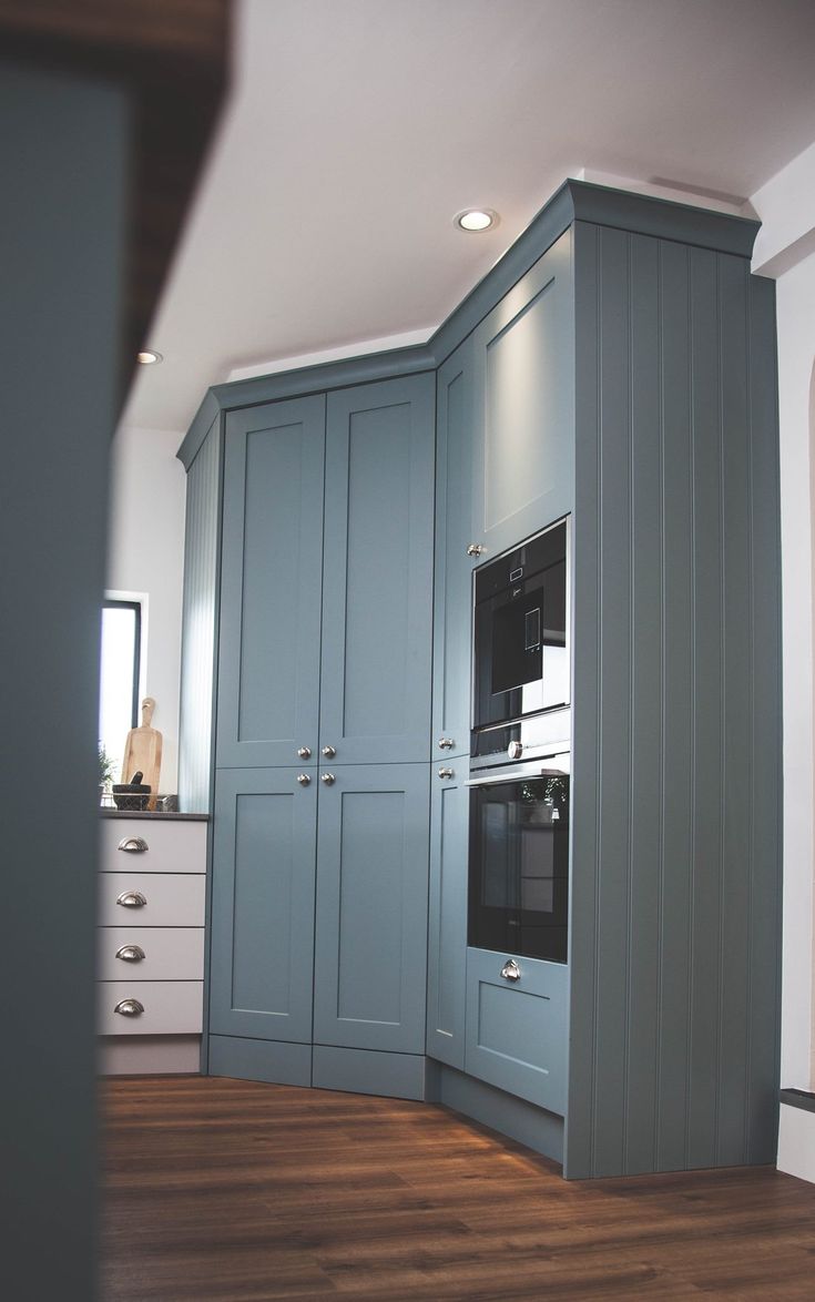 an empty kitchen with blue cabinets and wood flooring in the middle of the room