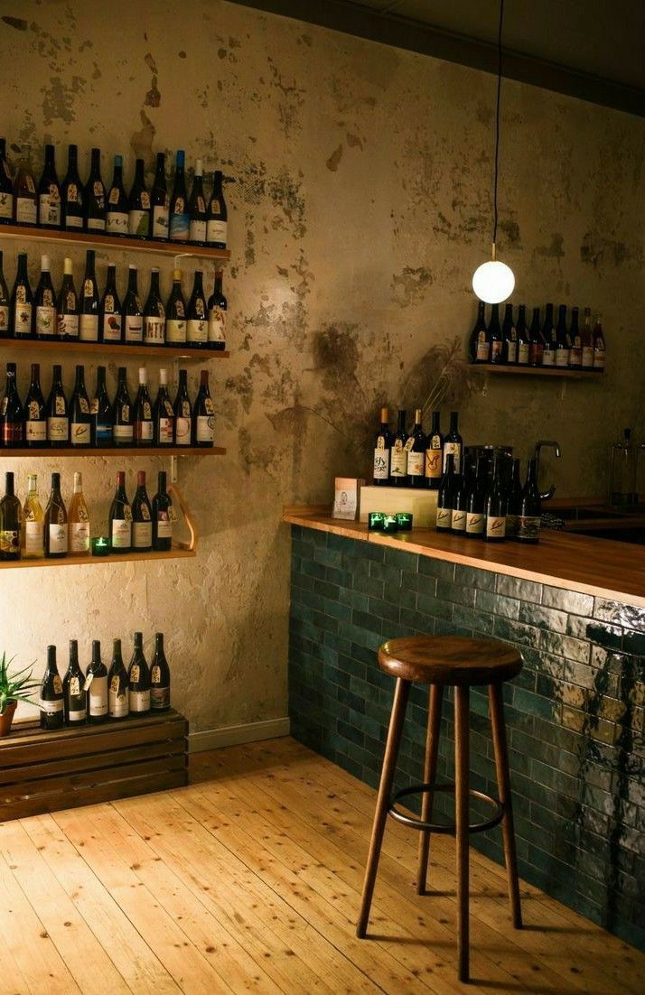 there is a bar with bottles on the wall and stools in front of it