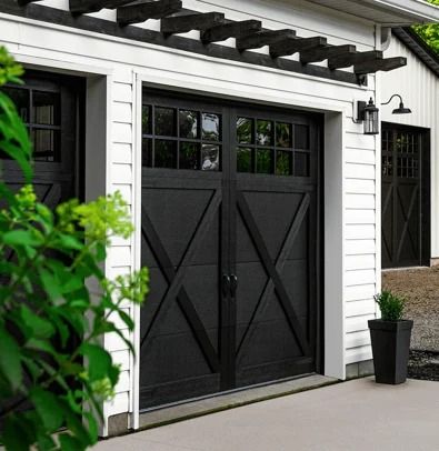 a black and white garage with two doors on each side, next to a planter