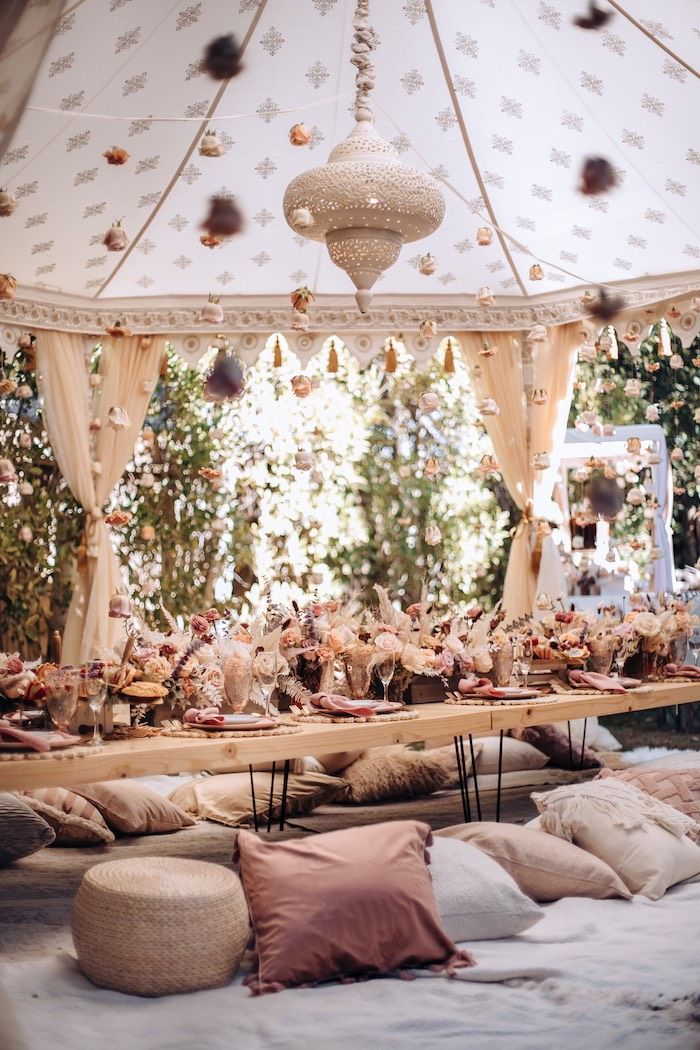 a bed with lots of pillows on top of it next to a table filled with food