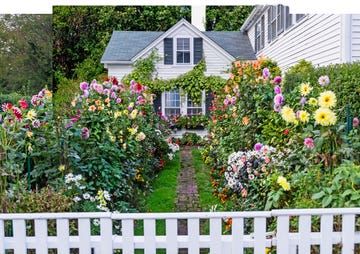 a white picket fence in front of a house with flowers growing on the top and bottom