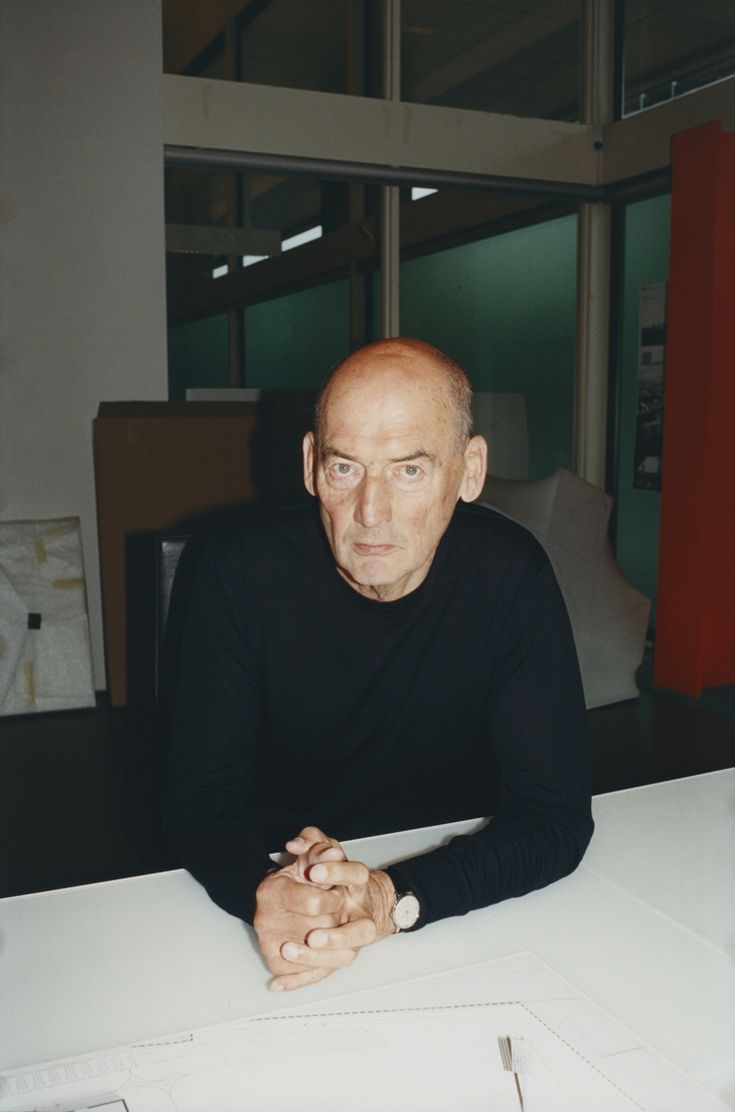 a man sitting at a table with a knife in his hand and looking off to the side