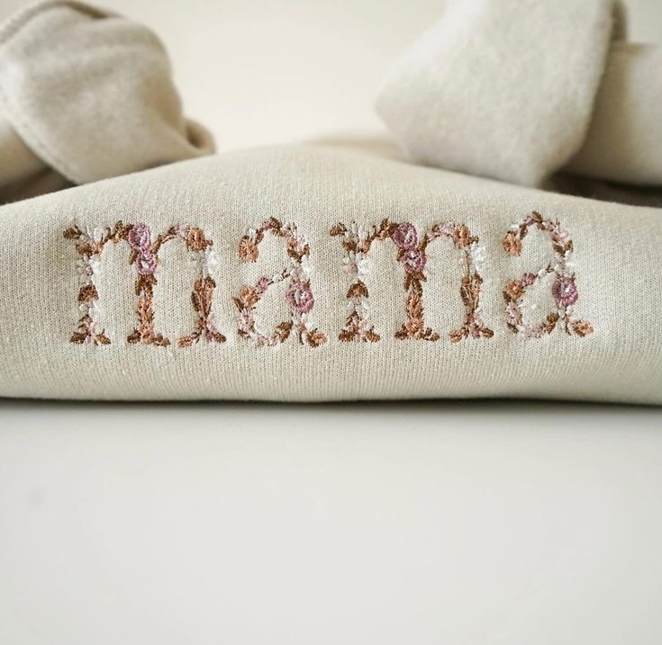 the word mama is embroidered onto a white pillow