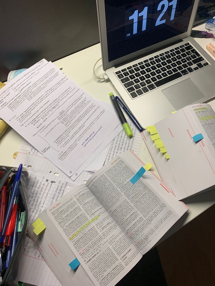 an open laptop computer sitting on top of a desk next to papers and pencils