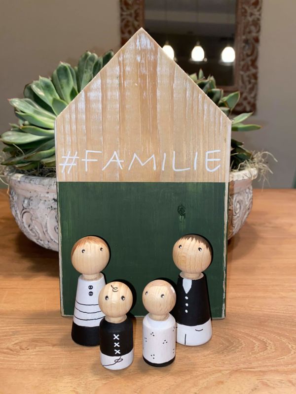 a family figurine sitting on top of a wooden table next to a potted plant