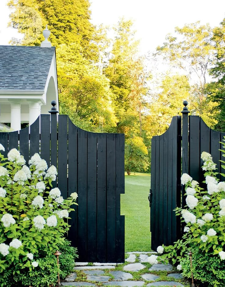 a black gate with white flowers in front of it