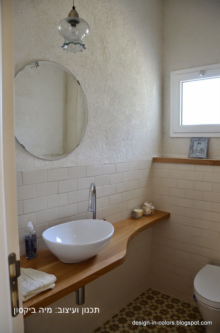 a bathroom with a sink, mirror and toilet in it's corner area next to a window