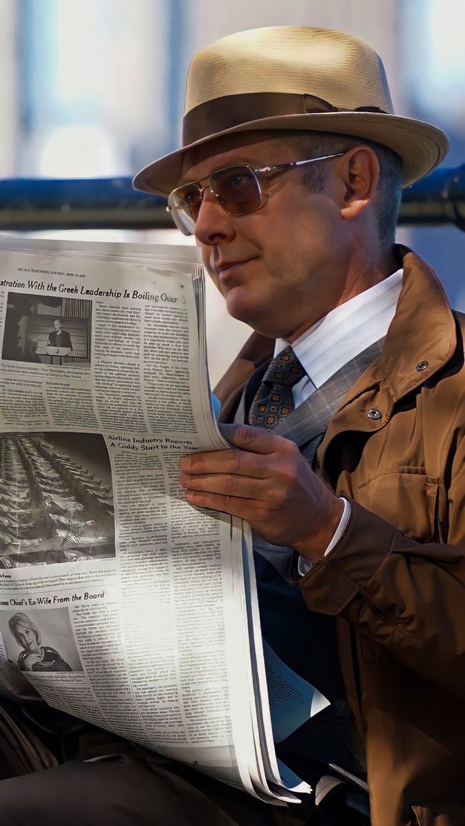 a man in a hat and glasses reading a newspaper