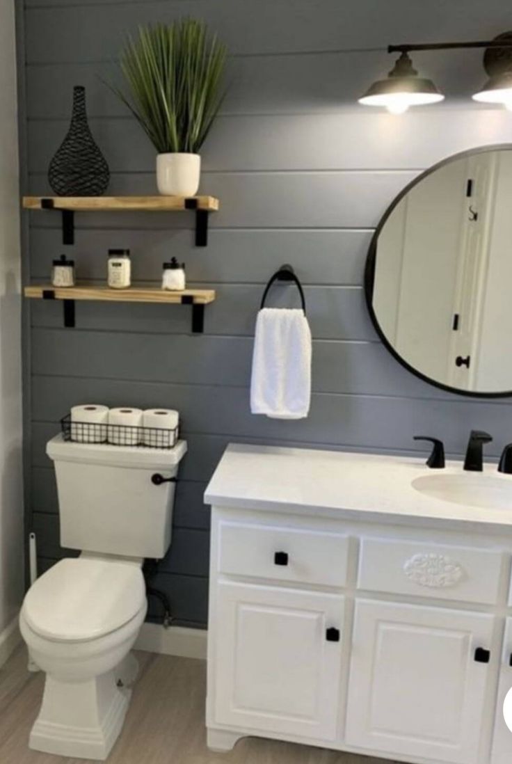 a white toilet sitting next to a sink in a bathroom under a mirror and lights