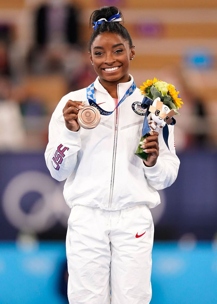 a woman holding a medal and flowers in her hand