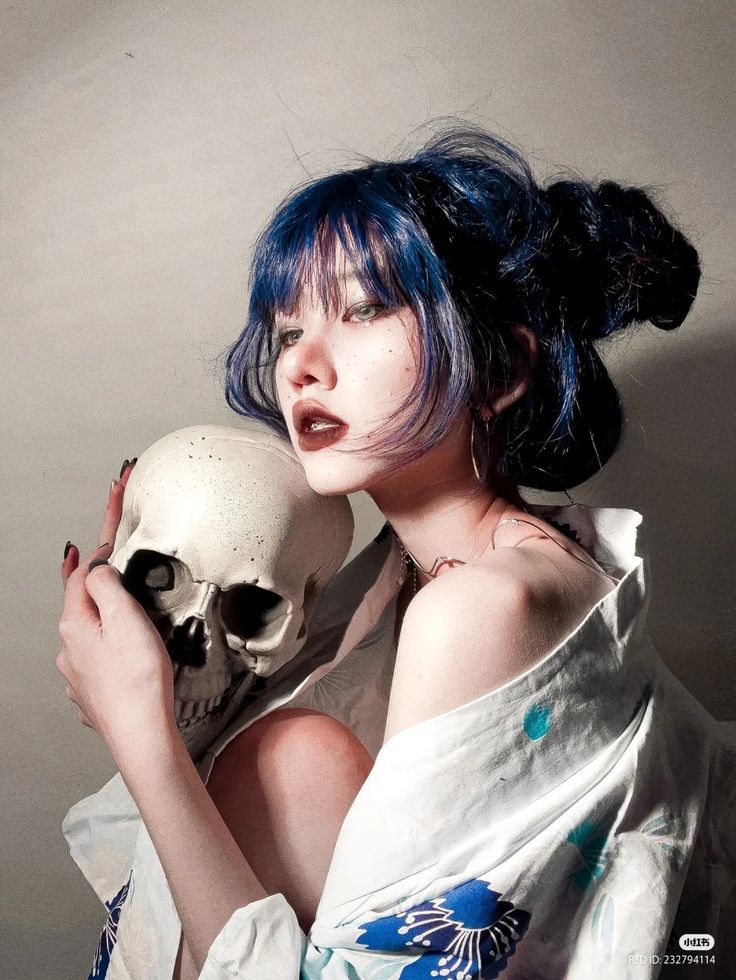 a woman with blue hair holding a skull