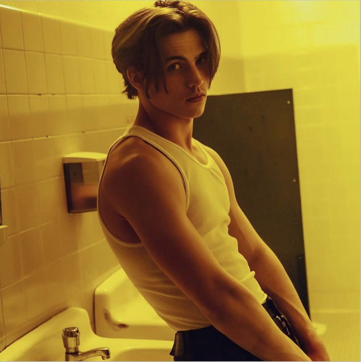 a young man standing in front of a bathroom sink