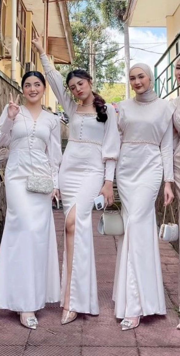 three women in white dresses posing for the camera with one woman wearing a hijab