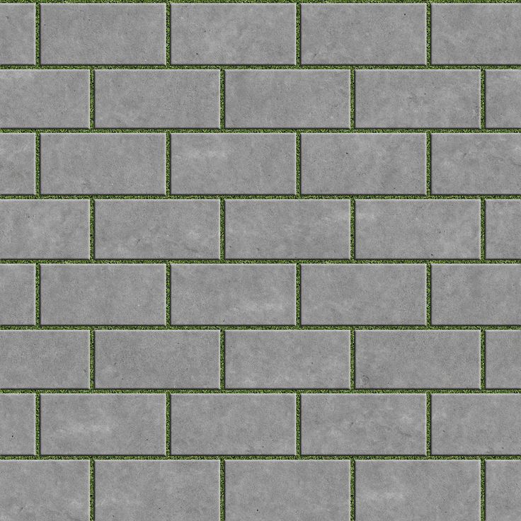 a gray brick wall with green grass growing on the top and bottom part in between