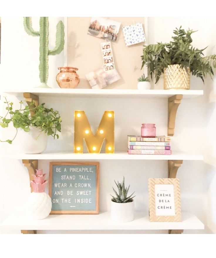 a white shelf topped with lots of books and plants