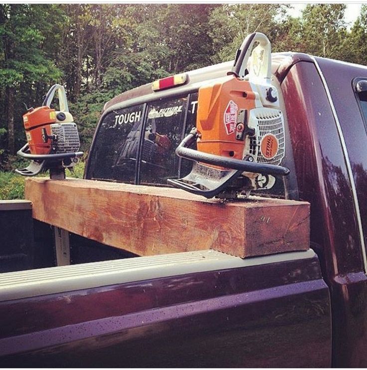 two chainsaws are on the back of a pickup truck with trees in the background