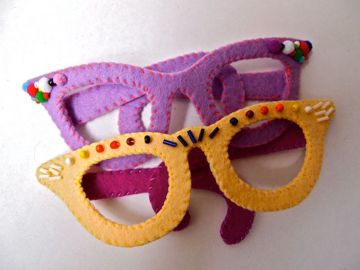 two purple and yellow masks with cat ears on top of each other, one wearing a pair of glasses