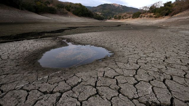 there is a small puddle in the middle of the desert floor with mountains in the background