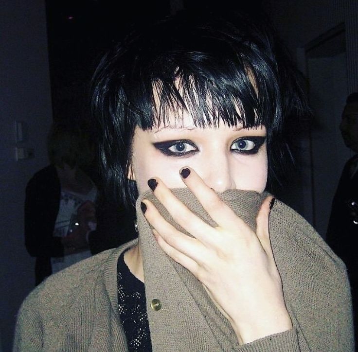 a woman with black hair and blue eyes covers her mouth