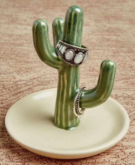 a green cactus ring sitting on top of a white plate next to a brown table