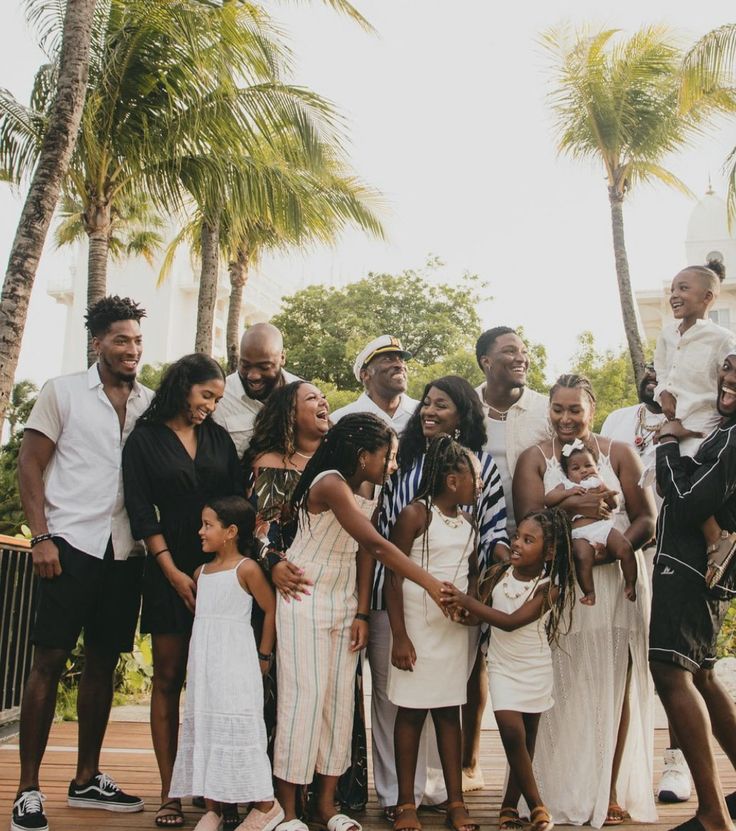 a group of people standing next to each other in front of trees and palm trees