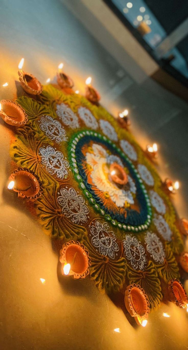 an intricately decorated diya with candles on the floor