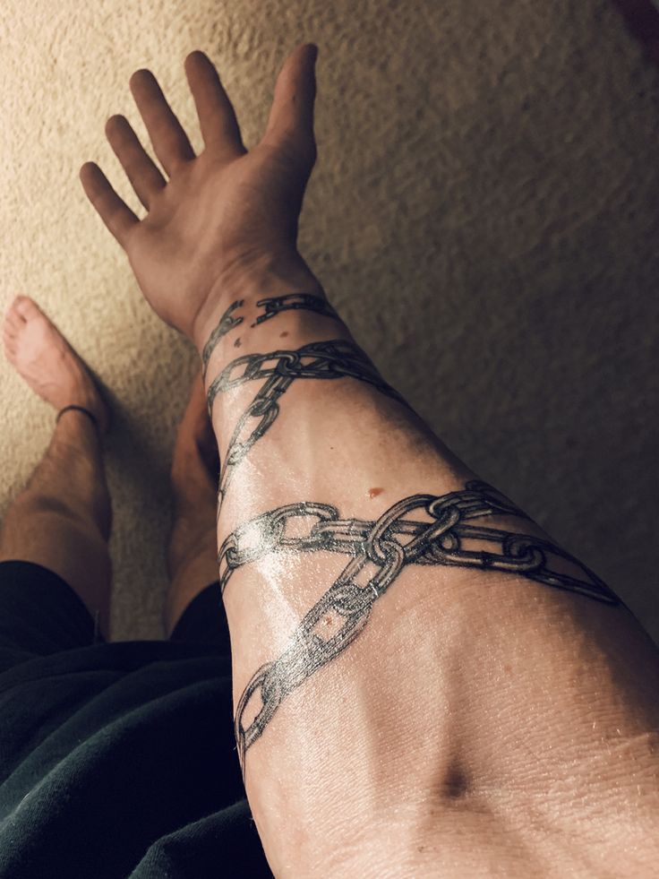 a man's arm with a chain tattoo on it