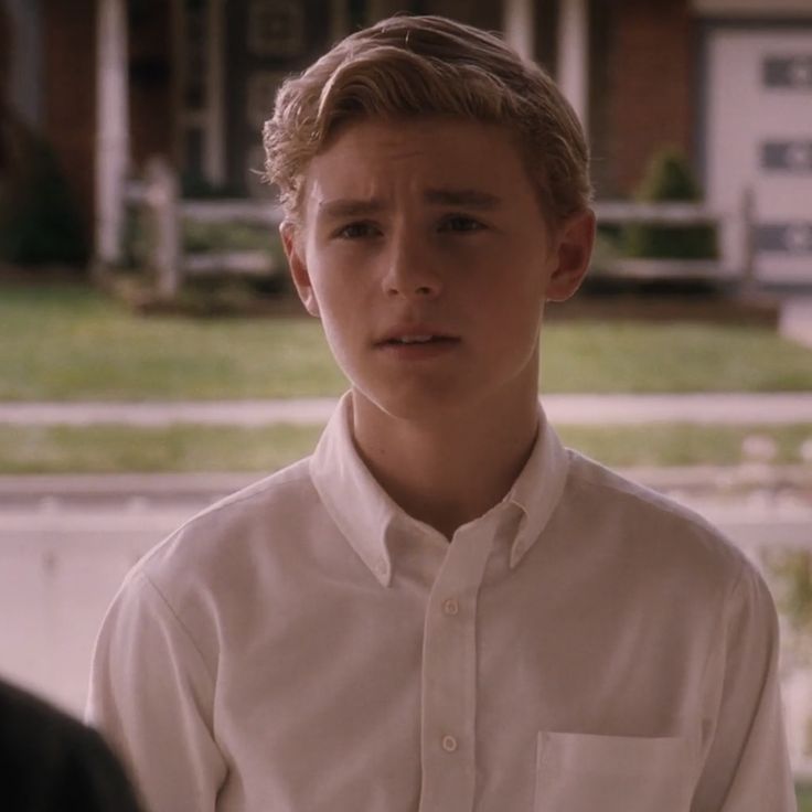 a young man standing in front of a house