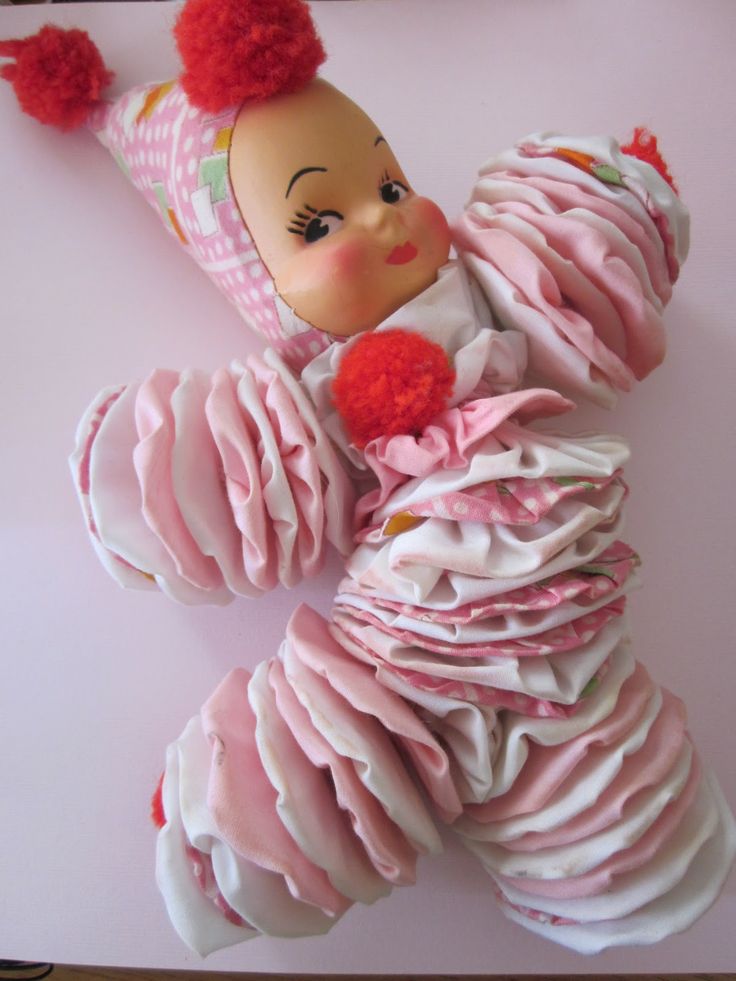 a baby doll made out of pink ruffles and a red pom - pom