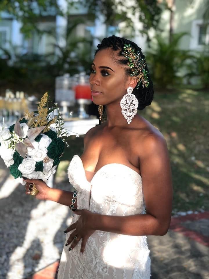 a woman in a wedding dress holding a bouquet of flowers and wearing large statement earrings