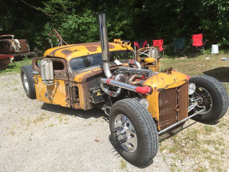 an old yellow truck parked on top of a gravel road