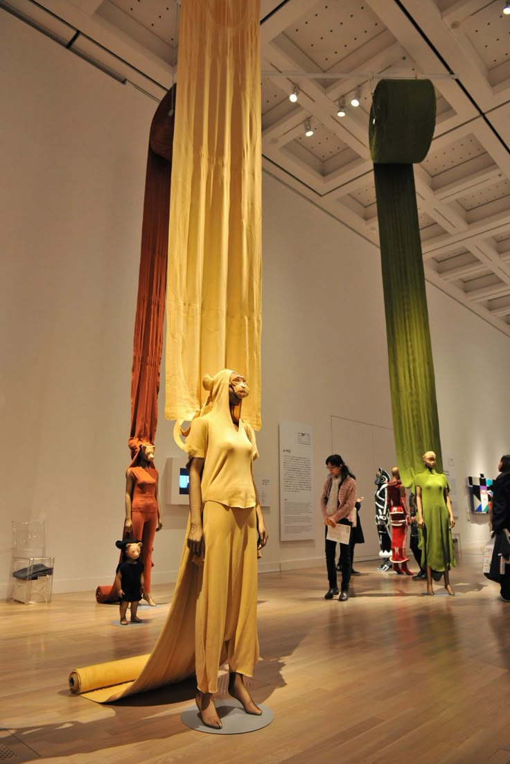 a group of people standing around in a museum looking at some art on the walls