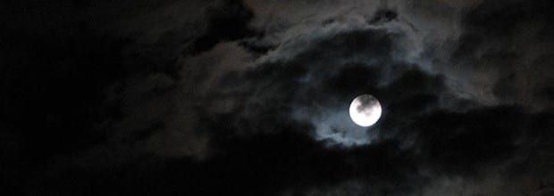 the moon is seen through some dark clouds