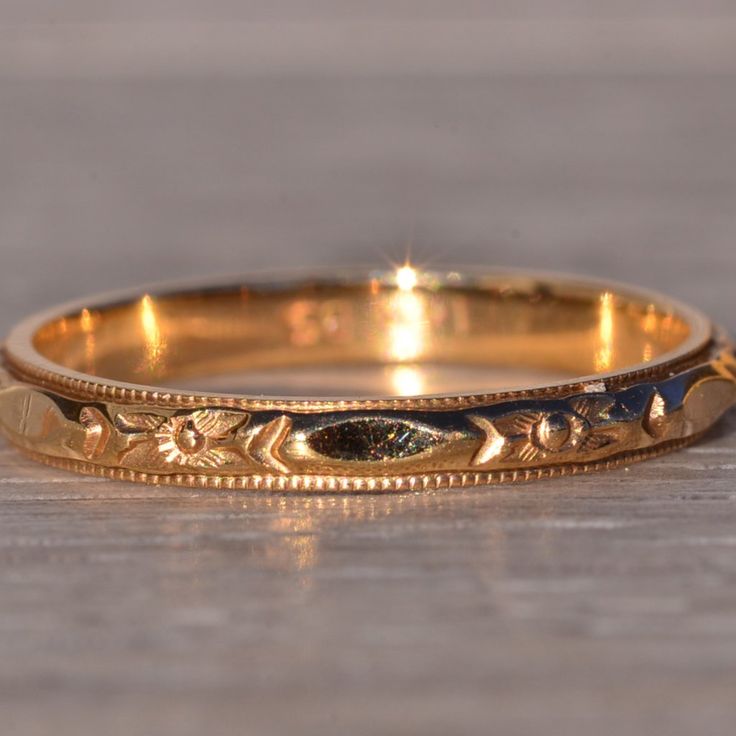 a close up of a gold wedding ring on a wooden surface with light shining in the background