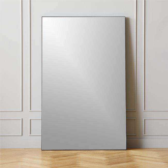 a mirror sitting on top of a hard wood floor next to a wall mounted cabinet