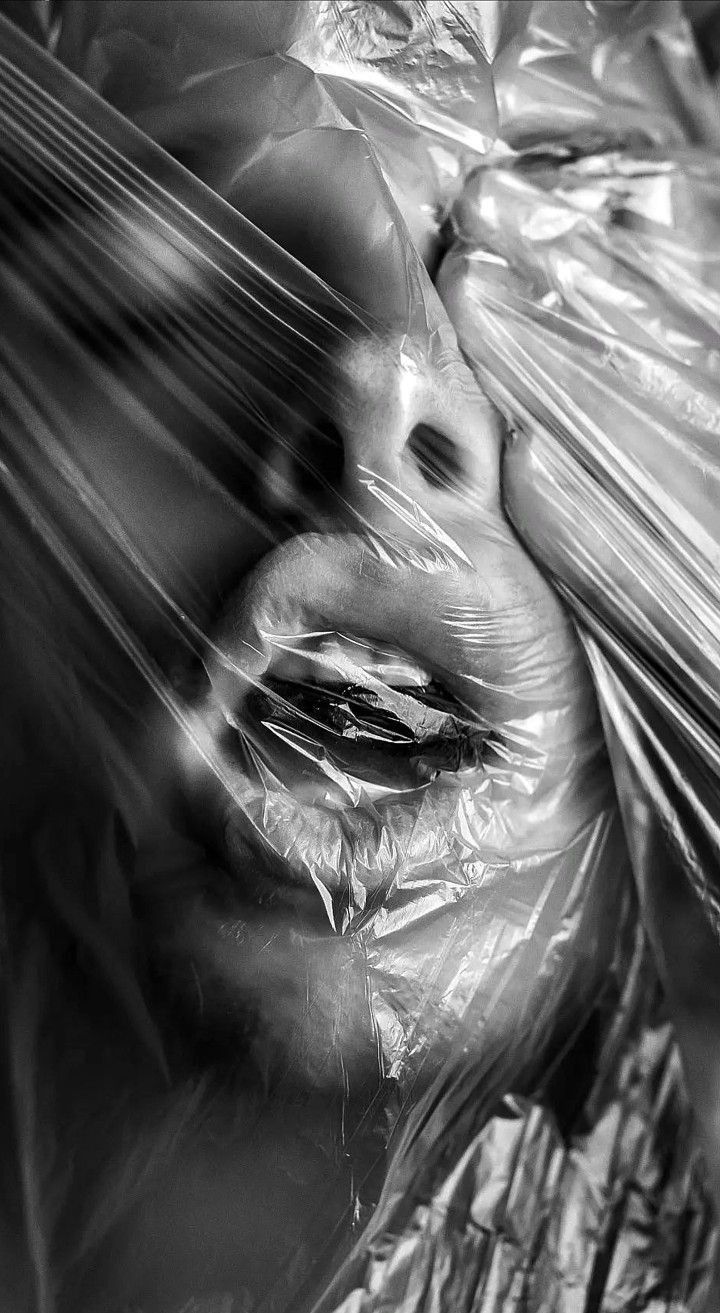 a black and white photo of a woman wrapped in plastic