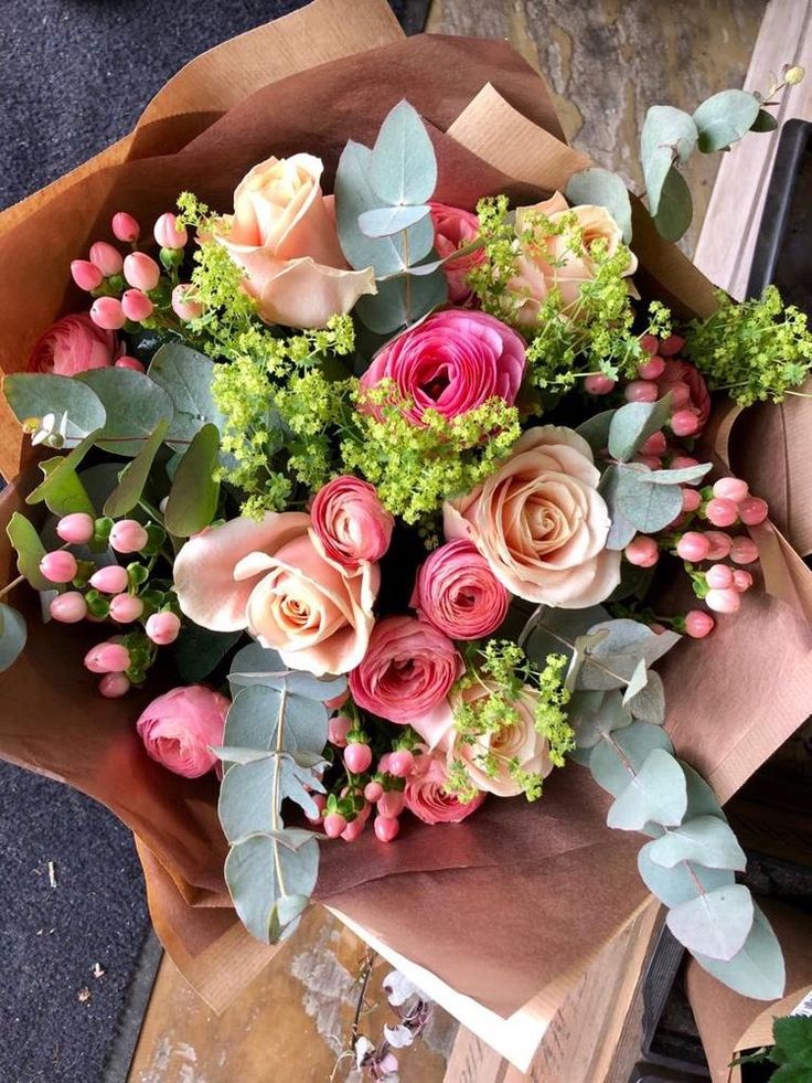 a bouquet of flowers sitting on top of a piece of brown paper with green leaves