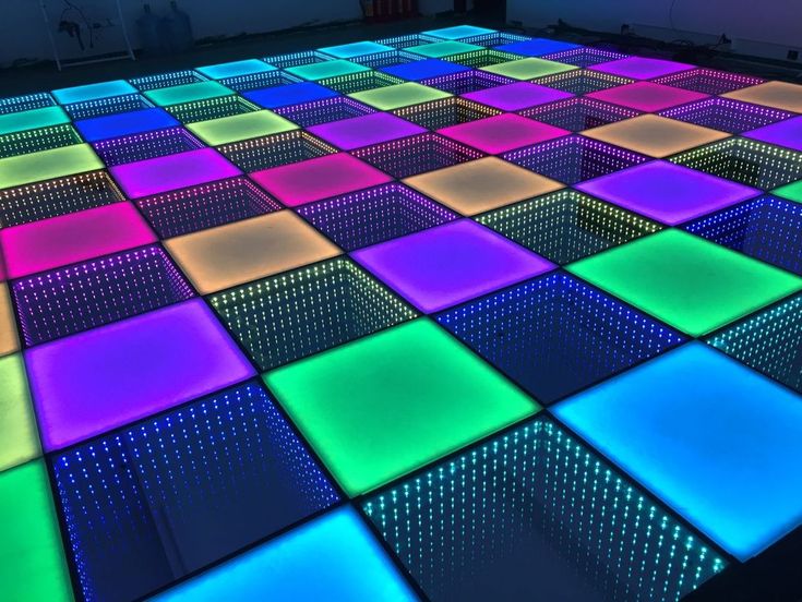 an illuminated dance floor with square tiles in the middle and neon lights on it's sides