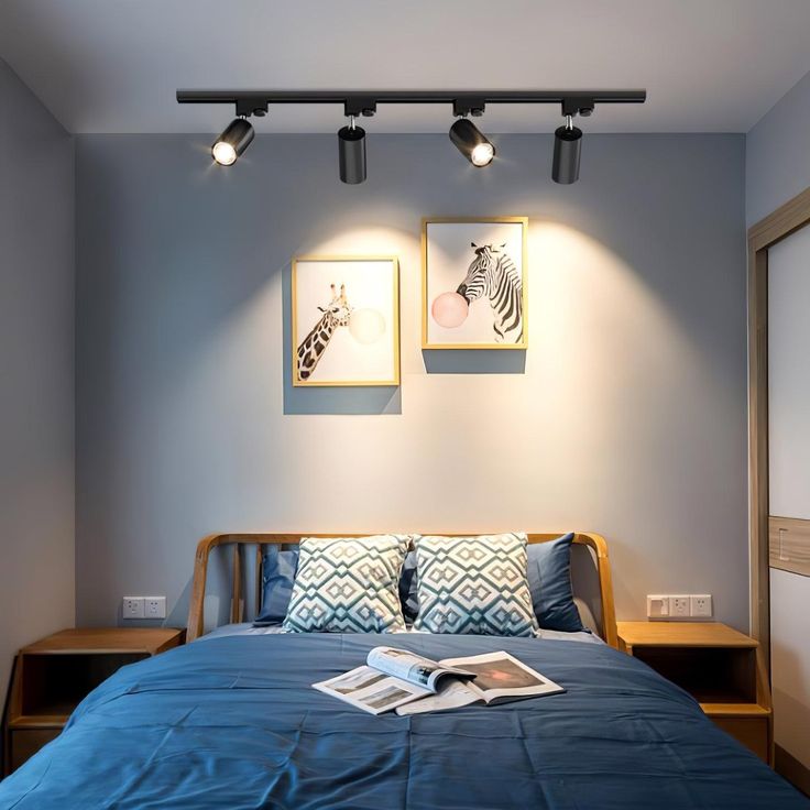 a bed with blue sheets and two pictures on the wall next to it in a bedroom