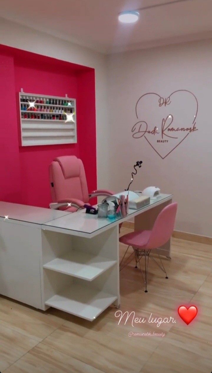 a pink and white nail salon with two chairs in front of the counter, one chair is up against the wall