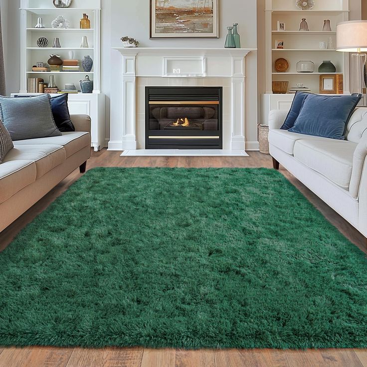 a living room with two couches and a green rug in front of a fireplace