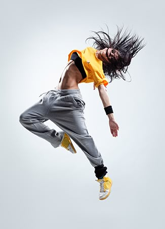 a man flying through the air while wearing a yellow shirt and grey sweatpants with his hair blowing in the wind