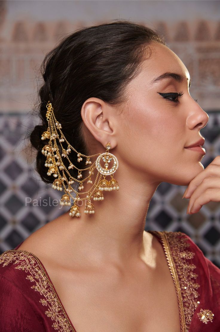 Experience the luxuriance of Gold-plated Kundan earrings, designed with an opulent Kundan-studded crescent motif outlined with shell pearls.  These  Sahara earrings are a straight-out-of-a-dream design, with long chains of small dangling jhumkis and pearls graciously moving with your steps. Entwined with time-honored customs and artful ingenuity, these Sahara Pearl earrings are the epitome of magnificence and poise. Closure - Push Back Weight- 76 gm (pair) Paisley Pop travels the depths of India to learn techniques and crafts from deep down in the local markets and villages. We give utmost importance to our quality and packaging. Our goal is to ensure you receive exactly what you are looking for and for your experience to be special and memorable. We are ready to help and advise you throug Earring To Hair Chain, Pearl Tassel Earrings Gold Indian, Luxury Latkans Dangle Earrings, Hairstyles With Earrings, Luxury Kundan Jhumkas In Temple Jewelry Style, Cheap Chandbali Earrings With Latkans, Luxury Bollywood Earrings For Diwali, Luxury Formal Necklace With Latkans, Luxury Latkans Earrings