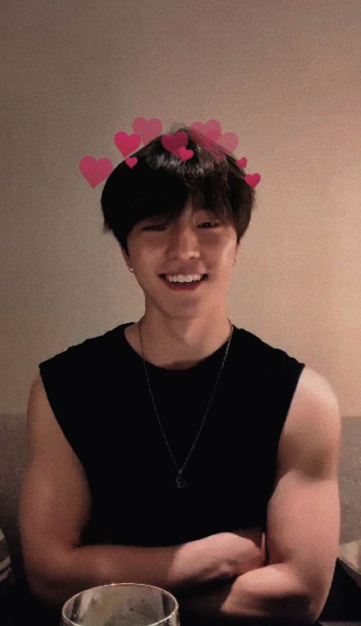 a young man sitting on top of a couch next to a bowl of food with hearts in his hair