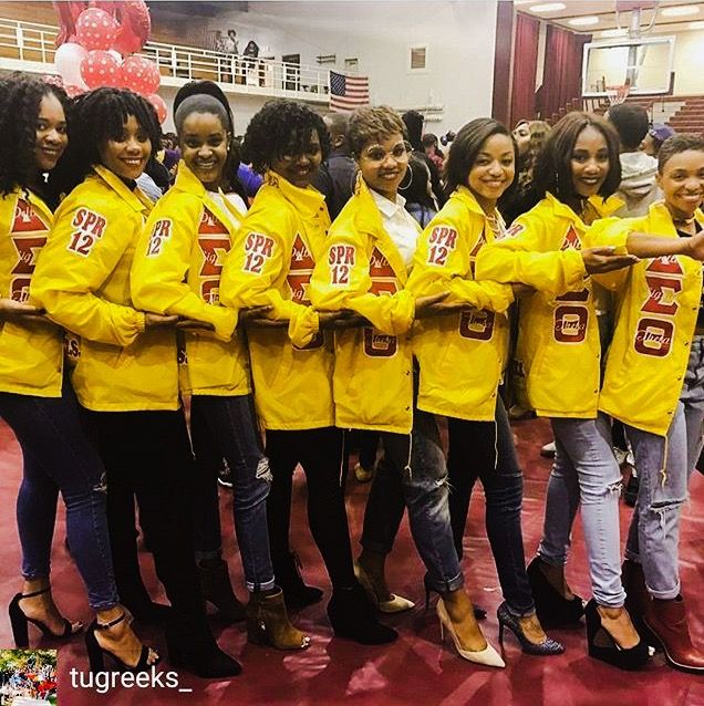 a group of young women in yellow jackets posing for a photo with one woman's hand on her hip