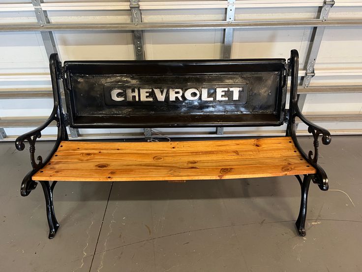 a bench with the word chevrolet on it sitting in front of a garage door,