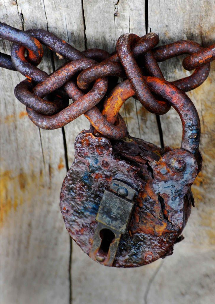 an old rusted padlock is hanging on a wooden door with chains attached to it